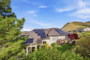 Rear view of house with solar panels, a mountain view, and roof with shingles