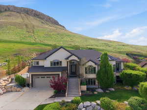 Bi-level home featuring stucco siding, a garage, concrete driveway, and a mountain view