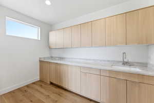 Kitchen with light wood finish cabinetry, light wood finished floors, light stone counters, modern cabinets, and recessed lighting