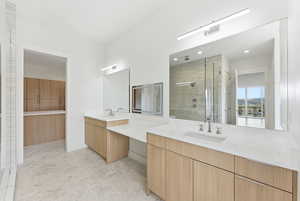 Full bathroom featuring two vanities, a shower stall, and a walk in closet