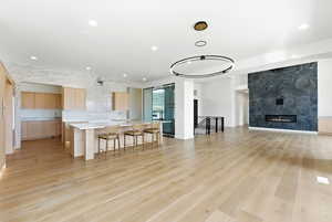 Kitchen featuring light wood finish cabinets, a kitchen island with sink, a breakfast bar area, modern cabinets, and a fireplace