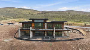 Rear view of house with a patio, a mountain view, and stone siding