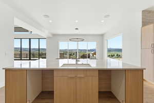 Kitchen with light wood finish cabinets, modern cabinets, light wood-style floors, light stone counters, and plenty of natural light