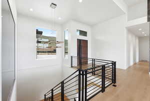 Corridor with light wood-style flooring, an upstairs landing, and recessed lighting