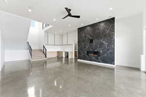 Unfurnished living room featuring ceiling fan, a high end fireplace, concrete flooring, recessed lighting, and beverage cooler