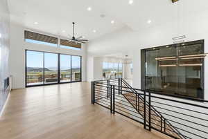 Hall with light wood finished floors, a high ceiling, a mountain view, recessed lighting, and an upstairs landing