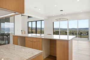 Kitchen featuring modern cabinets, a mountain view, a kitchen island with sink, and light wood finish cabinetry
