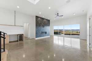 Unfurnished living room with concrete flooring, a ceiling fan, recessed lighting, beverage cooler, and a premium fireplace