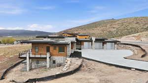 View of front facade featuring stone siding, a mountain view, area for grilling, roof mounted solar panels, and concrete driveway