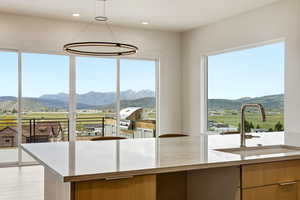 Kitchen featuring a mountain view, light stone counters, and pendant lighting