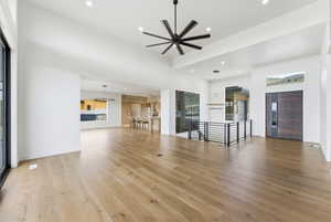 Unfurnished living room with a ceiling fan, a high ceiling, light wood-style flooring, plenty of natural light, and recessed lighting