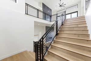 Staircase featuring wood finished floors, a high ceiling, a ceiling fan, and recessed lighting