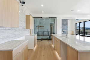 Kitchen featuring light wood finish cabinetry, light stone counters, light wood finished floors, and recessed lighting