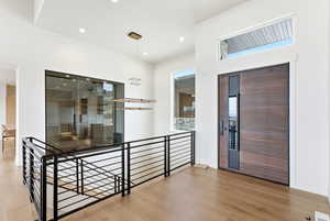 Hallway with light wood-type flooring, an upstairs landing, and recessed lighting