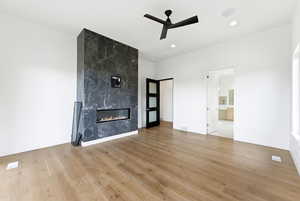 Unfurnished living room featuring light wood-type flooring, a premium fireplace, a ceiling fan, and recessed lighting