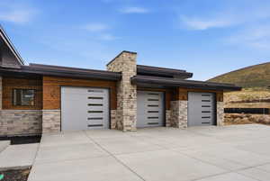 View of front of house with stone siding, a garage, and driveway
