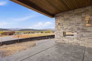 View of yard featuring an outdoor stone fireplace, a mountain view, and a patio