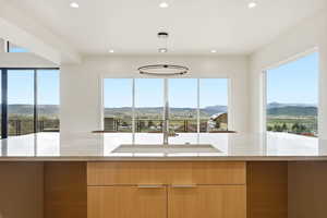 Kitchen with modern cabinets, light stone countertops, a mountain view, and healthy amount of natural light