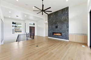 Unfurnished living room featuring light wood finished floors, ceiling fan, a fireplace, and recessed lighting