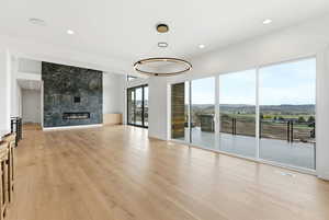Unfurnished living room featuring a mountain view, a fireplace, recessed lighting, and light wood-type flooring