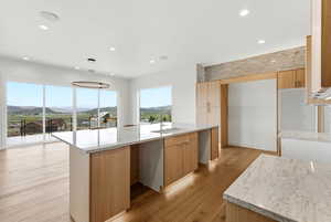 Kitchen featuring light stone counters, light wood finished floors, modern cabinets, and hanging light fixtures