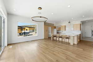 Kitchen featuring a kitchen bar, a kitchen island with sink, light wood finish cabinets, modern cabinets, and light wood-type flooring