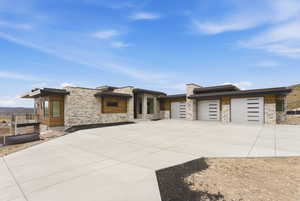 Contemporary home featuring concrete driveway, a garage, and stone siding
