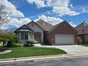 View of front of house featuring a front lawn, a garage, driveway, and brick siding