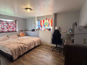 Bedroom featuring a textured ceiling, wood finished floors, and an office area