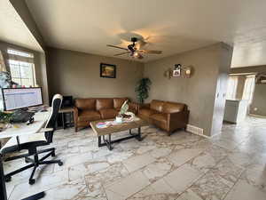 Living area with a textured ceiling, light marble finish floors, a ceiling fan, and an office area
