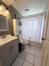 Bathroom with vanity, a textured ceiling, shower / bath combo, and light tile patterned flooring