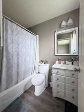Full bath featuring vanity, dark wood-type flooring, and shower / tub combo with curtain