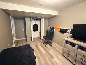 Bedroom with light wood-style floors, a textured ceiling, and a closet