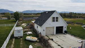 View of front of house featuring a rural view, a mountain view, a garage, concrete driveway, and roof with shingles