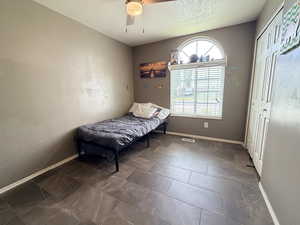 Bedroom with a textured ceiling, a ceiling fan, and a closet