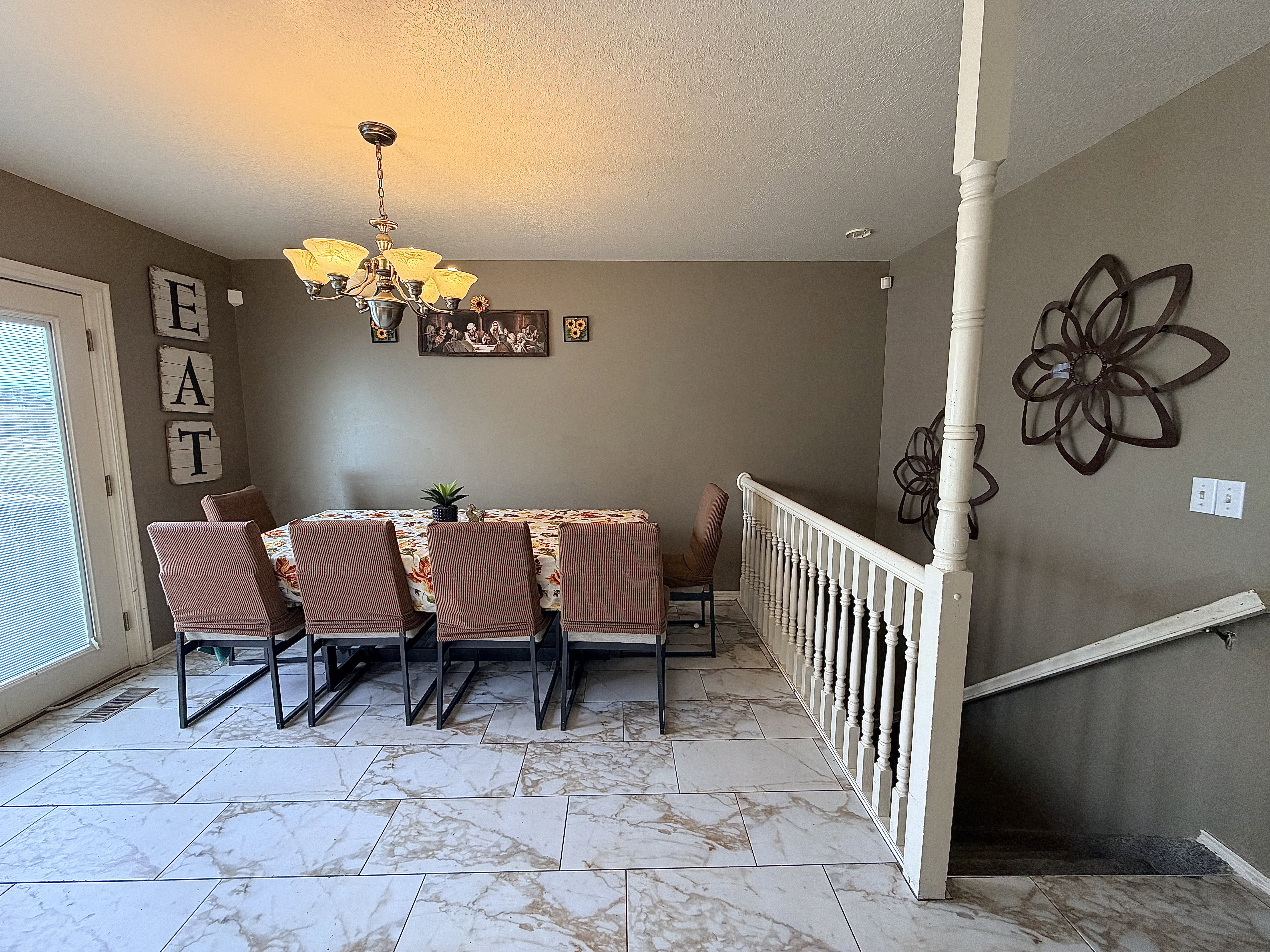 Dining room featuring a chandelier, a textured ceiling, and light marble finish floors