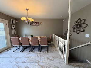 Dining room featuring a chandelier, a textured ceiling, and light marble finish floors