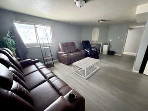 Living room with wood finished floors, a textured ceiling, and wainscoting
