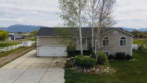 View of front facade featuring a mountain view, stucco siding, concrete driveway, and an attached garage