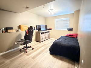 Bedroom with light wood-style floors, a textured ceiling, and a desk
