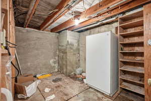 Unfinished basement featuring freestanding refrigerator