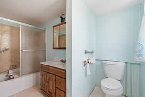 Bathroom featuring light flooring, bath / shower combo with glass door, and vanity