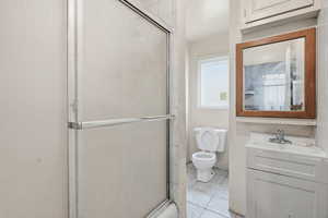 Full bathroom featuring vanity, a shower with shower door, and light tile patterned floors