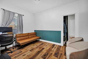 Home office featuring hardwood / wood-style floors, a wainscoted wall, and a decorative wall