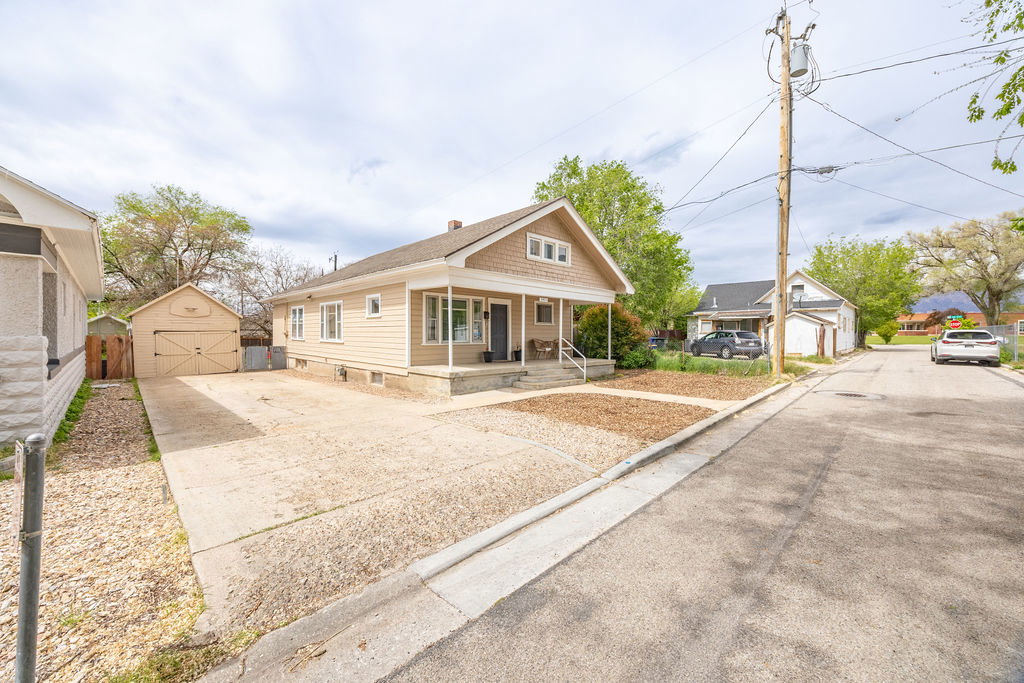 Bungalow-style home with an outbuilding, a porch, driveway, and a detached garage