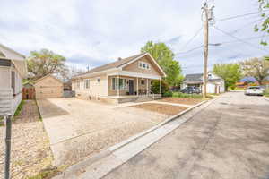 Bungalow-style home with an outbuilding, a porch, driveway, and a detached garage