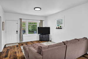 Living room featuring dark wood finished floors and baseboards