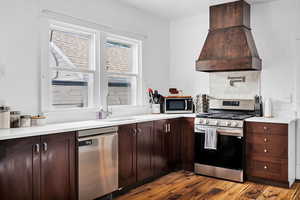 Kitchen featuring stainless steel appliances, dark wood finish cabinetry, dark wood-style flooring, and tasteful backsplash