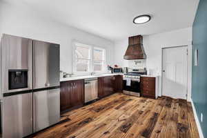 Kitchen featuring stainless steel appliances, dark wood finished floors, light countertops, and dark wood finish cabinetry