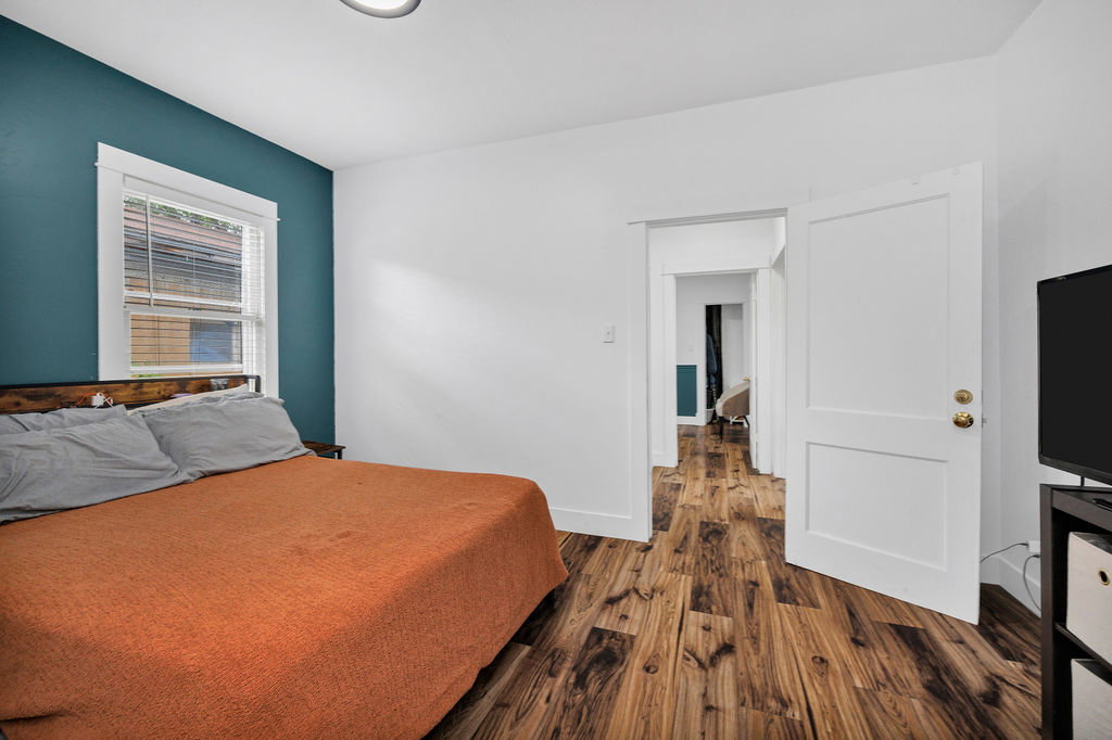 Bedroom with dark wood-style flooring and baseboards